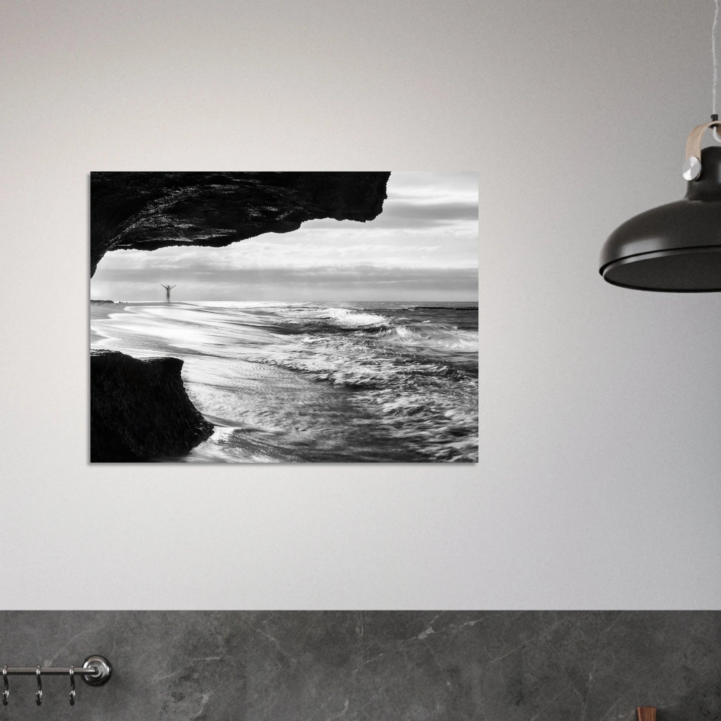 Lone figure with arms outstretched inside a sea cave at the Atlantic edge of Aguadilla, Puerto Rico — black-and-white long-exposure fine art print by Abimael Medina.